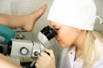 Colposcopia Una doctora usa un colposcopio para observar el cuello uterino de una paciente
