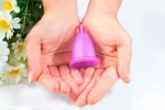 Copa menstrual, alternativa a tampones y compresas Manos de mujer sosteniendo una copa menstrual