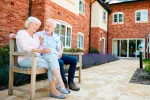 Senior cohousing, vivienda colaborativa para mayores Pareja de personas mayores junto a una vivienda colaborativa