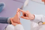 Médico revisando los pies deformados de una niña