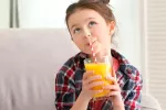 Niña bebiendo un zumo de naranja