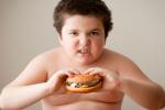 Niño obeso comiendo una hamburguesa