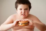 Niño obeso comiendo una hamburguesa