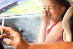 Persona fumando en el coche junto a su hija