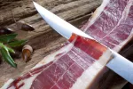 Cuchillo cortando una loncha de jamón ibérico