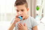Niño asmético usando un inhalador