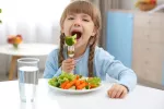 Niña vegetariana comiendo brócoli