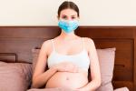 Embarazada en la cama con una mascarilla anti-covid-19