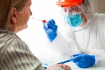 Médico con equipo de protección personal realizando una prueba de PCR