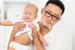 Los bebés y niños expuestos al tabaco sufren envejecimiento acelerado Padre fumando junto a su bebé