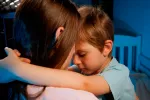 Madre consolando a su hijo asustado en la cama
