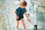 Niño mojándose en chorros de agua por la de calor