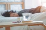 Mujer dormida junto a un vaso de agua y pastillas