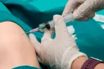 Médico inyectando esteroides en una rodilla con artritis