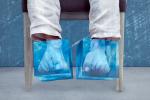 Una persona sentada con unas bolsas para congelar en los pies