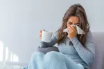 La nariz esconde el motivo por el que hay más resfriados en invierno Mujer resfriada se suena la nariz y bebe algo caliente