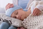 Curan la leucemia infantil por primera vez con células CAR T editadas Niño con leucemia durmiendo sobre las piernas de su madre