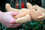 Una mujer sosteniendo un peluche en el entierro de su hijo