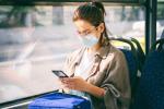 Mujer con mascarilla leyendo el móvil en el autobus