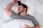 Dormir menos de 6 horas reduce la efectividad de las vacunas Varón dormido junto a su teléfono móvil