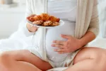 Asocian el exceso de calorías en el embarazo con sobrepeso en el hijo Mujer embarazada con un plato de bollos industriales