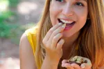 Tomar más magnesio en la dieta diaria ayuda a prevenir la demencia Chica joven comiendo anacardos