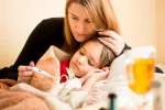 Revelan la posible causa del brote de hepatitis aguda grave infantil Madre tomando la temperatura a su hija enferma de gripe