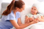 Hallan un posible tratamiento para un cáncer cerebral infantil mortal Enfermera hablando con una niña enferma de cáncer