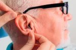 Usar audífono reduce el riesgo de demencia asociado a la sordera Doctor colocando un audífono a un paciente
