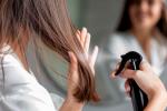 Mujer joven aplicando alisador químico a su pelo