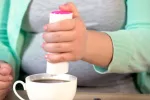 Mujer obesa echando edulcorante a su taza de té