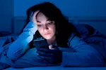Vinculan usar las redes sociales por la noche y el retraso en el sueño Chica joven leyendo sus redes sociales en la cama por la noche