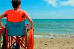 Joven en una silla de ruedas mirando al mar