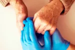 Doctor cogiendo las manos de paciente mayor