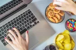 Así hace el estrés crónico que tu cerebro tenga antojo de dulces Persona cogiendo comida mientras trabaja