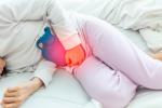 Mujer tumbada en la cama con síntomas de cistitis