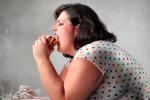 Mujer con sobrepeso comiendo una hamburguesa