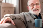 Hombre anciano sonriente bebiendo una taza de café