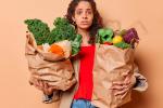 Mujer con bolsas de compra repletas de verduras y frutas