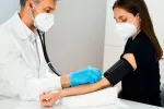 Un estudio muestra que el 21% de los pacientes que fueron ingresados en el hospital por COVID-19 han desarrollado hipertensión arterial posteriormente. Doctor tomando la tensión una paciente con síntomas de Covid-19