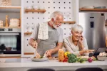 Cambios en la dieta pueden mejorar la salud durante el envejecimiento Pareja de adultos mayores cocinan alimentos saludables consultando una tablet
