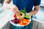 Persona joven comiendo humus con verduras