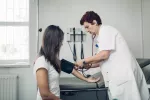 Doctora tomando la tensión a una chica joven