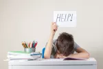 Estrés en los niños: cómo ayudar a tus hijos a gestionarlo Niño sentado en su escritorio con la cabeza agachada y pidiendo ayuda