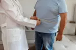 Doctor midiendo el perímetro abdominal a un hombre de mediana edad