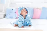 Bebé sonriendo sobre la cama de sus padres