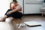 Los pacientes obesos recuperan mucho peso cuando dejan de tomar Zepbound Persona obesa con gesto triste junto a la báscula de peso