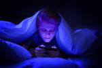 Adolescente usando el smartphone por la noche en la cama