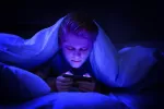 Adolescente usando el smartphone por la noche en la cama