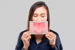 Aftas bucales persistentes: cómo tratarlas y prevenirlas Mujer sosteniendo una hoja impresa con una lengua infectada por úlceras